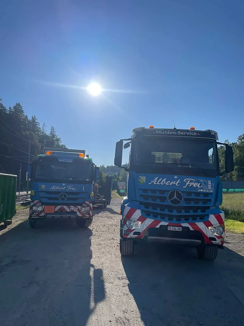 Zwei Lastwagen von Alb. Frei im Gegenlicht auf einer Baustellenzufahrt