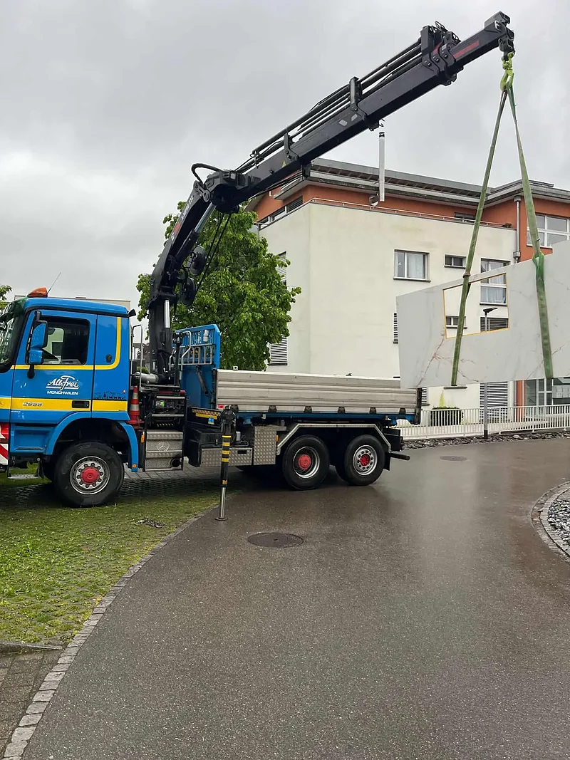 Kranwagen von Alb. Frei hebt Material an einem Neubau