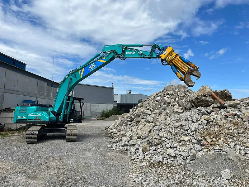 Kobelco-Abbruchbagger mit Sortiergreifer auf einem Betonabbruch-Haufen