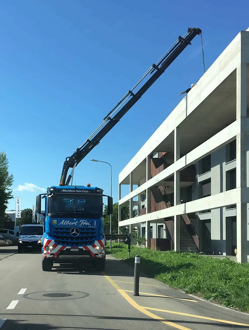 Kranwagen von Alb. Frei mit weit ausgefahrenem Ladekran an einem Wohnblock
