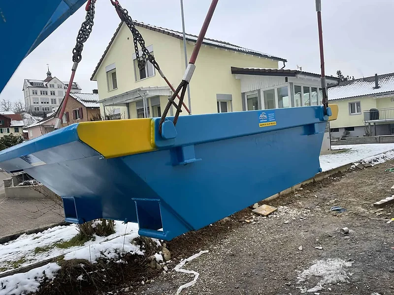 Welaki-Mulde am Muldenwagen vor einem Wohnhaus im Schnee