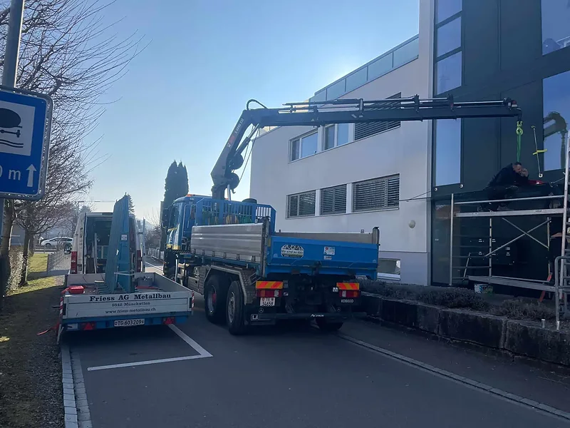 Kranwagen von Alb. Frei lädt Material an einem Geschäftshaus