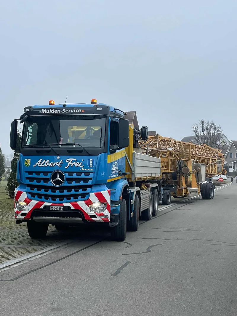 Kranlastwagen von Alb. Frei mit Baukranteilen in einer Quartierstrasse