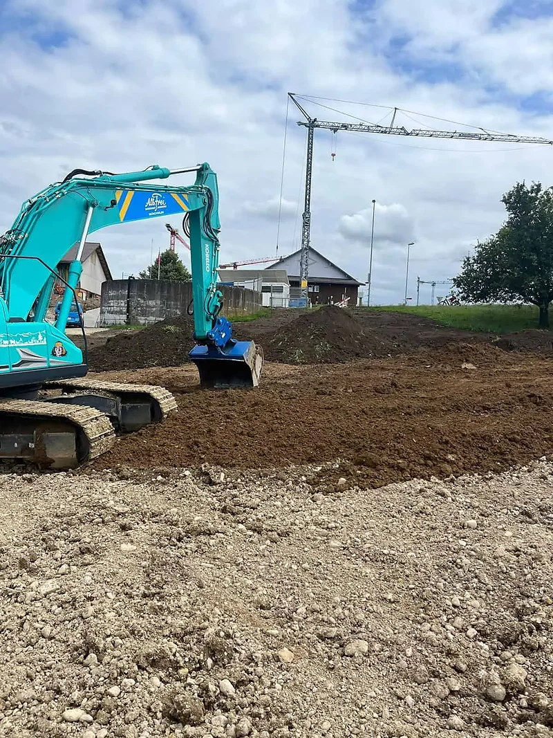 Kobelco-Bagger beim Aushub vor einem Wohnquartier