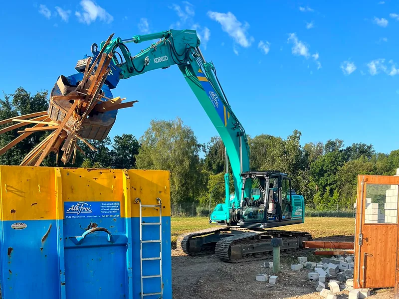 Bagger verlädt Altholz beim Rückbau direkt in die Mulde