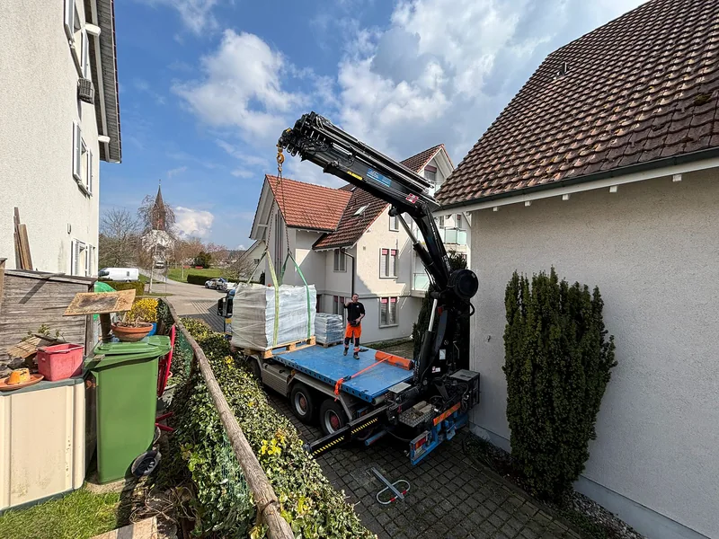 Kranwagen versetzt Paletten in einem engen Wohnquartier