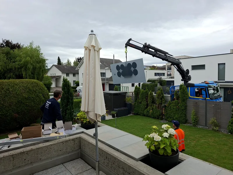 Kran setzt eine Platte mit dem Vakuumheber im Garten