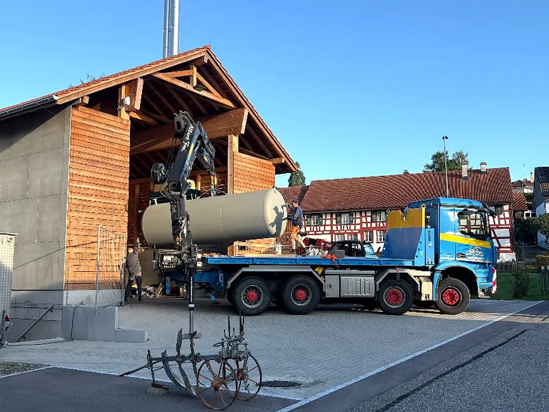 Kranwagen hebt einen Tank in eine Scheune