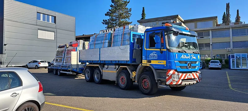 Kranlastwagen mit Tieflader vor einem Werkhof