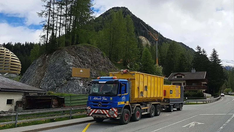 Abrollkipper von Alb. Frei mit gelbem Container im Bergtal